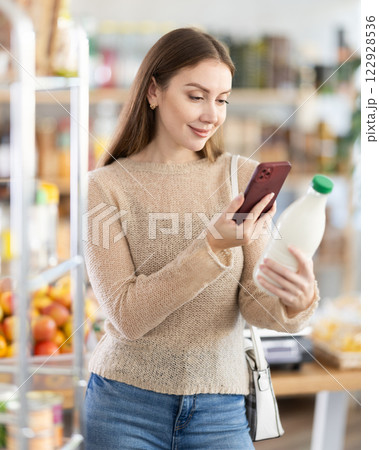 Female buyer scans QR code on milk label in grocery store Female buyer scans QR code on milk label in grocery store 122928536