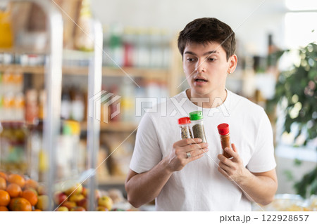 Guy examining bottles of spice bottles at grocery store Guy examining bottles of spice bottles at grocery store 122928657