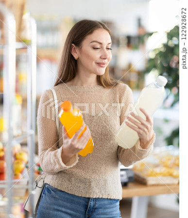 Female shopper chooses bottle of sweet water while shopping at supermarket Female shopper chooses bottle of sweet water while shopping at supermarket 122928672