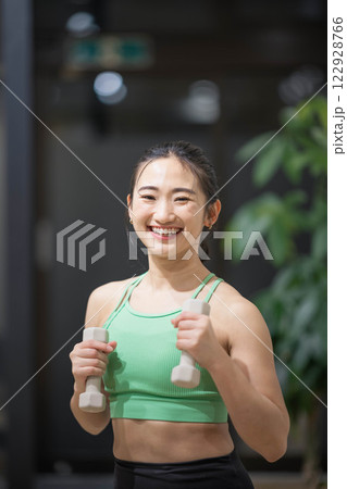 トレーニングウェアを着てダンベルで筋トレをしている若い女性 122928766