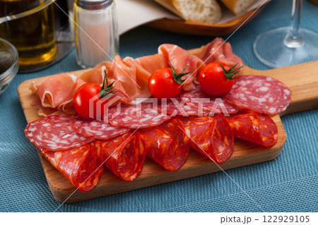 Spanish tasty meal slicing sausages and jamon with tomatoes, close up 122929105