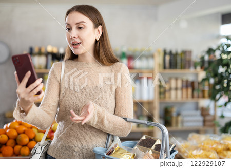 Young woman having video chat during shopping in grocery store 122929107