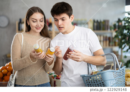 Happy carefree young couple looking smoothie in local grocery store 122929148