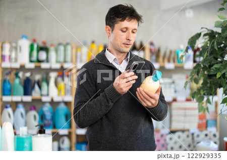 Middle-aged woman scanning QR-code on detergent at supermarket 122929335