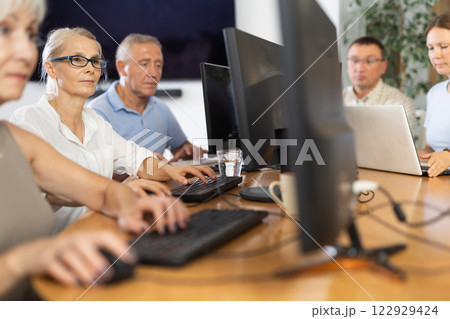 Side view of mature people while studying in computer lab in nursing home 122929424