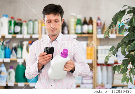 man scans the barcode of the label of a detergent man scans the barcode of the label of a detergent 122929450