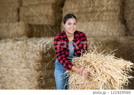 Cheerful woman farmer holding bunch of hay 122929560