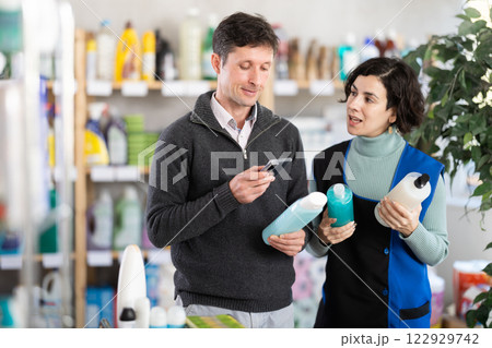 Woman seller help man visitor scan QR code, get information about shower gel in mobile app Woman seller help man visitor scan QR code, get information about shower gel in mobile app 122929742