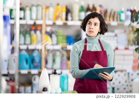 Middle-aged woman taking record of inventory in household store 122929908