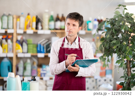 Middle-aged marketer taking record of inventory in household store Middle-aged marketer taking record of inventory in household store 122930042