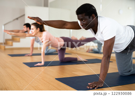 African american doing Dandayamna Bharmanasana during group yoga workout African american doing Dandayamna Bharmanasana during group yoga workout 122930086