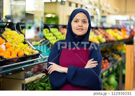 Young woman seller in hijab posing in grocery store Young woman seller in hijab posing in grocery store 122930191