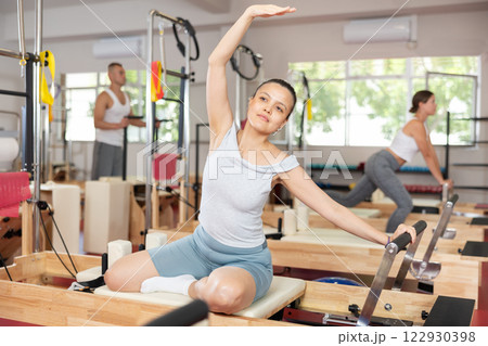 Young woman doing stretching on pilates machine 122930398