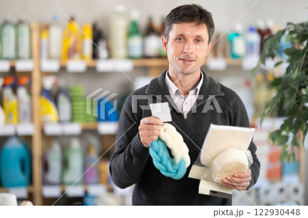 Among shop windows, man buyer leisurely examines goods and chooses body washcloth Among shop windows, man buyer leisurely examines goods and chooses body washcloth 122930448