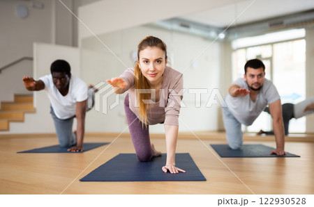 Woman and men practising bird dog exercise in fitness studio Woman and men practising bird dog exercise in fitness studio 122930528