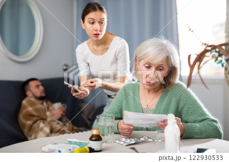 Young wife and an elderly mother discuss what medicines are needed for sick husband 122930533