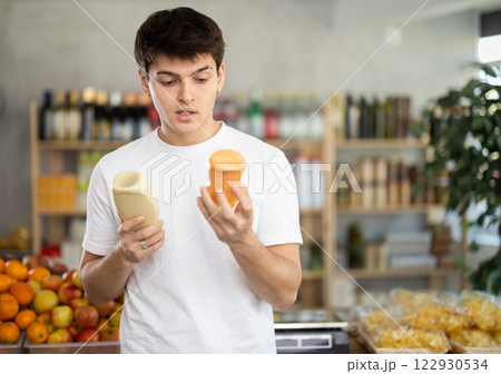 Choose food in supermarket - guy chooses mayonnaise to buy in the grocery department section of store 122930534