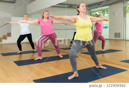 Women practicing yoga - virabhadrasana pose 122930562