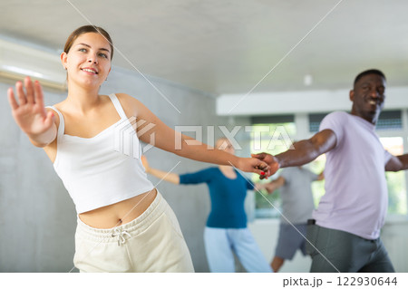 Girl teacher dances pair dance with african male student of fitness class 122930644
