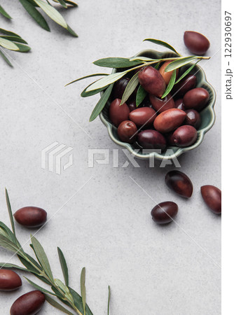 Kalamata olives with olive branch in green bowl on marble background 122930697