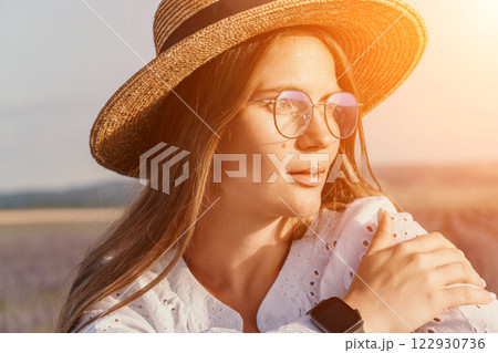 Woman Lavender Field Summer: Portrait, sunlit woman wearing hat and glasses, enjoying nature's beauty during summer. Woman Lavender Field Summer: Portrait, sunlit woman wearing hat and glasses, enjoying nature's beauty during summer. 122930736