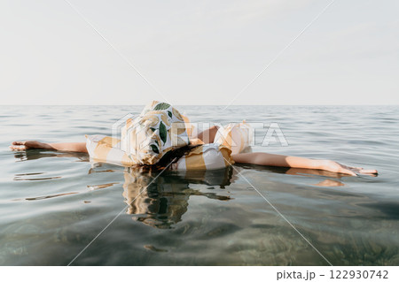 Woman Floating Water Relaxation - A woman floats in calm water, enjoying a relaxing experience. 122930742