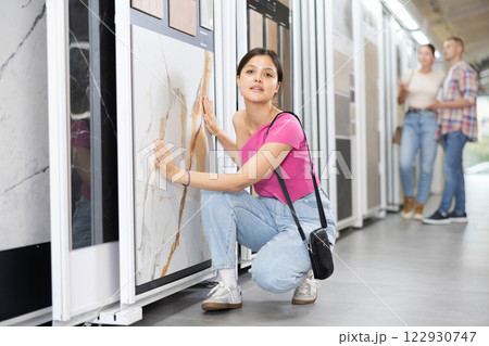 Asian woman browsing ceramic tiles on sliding display panels in store 122930747