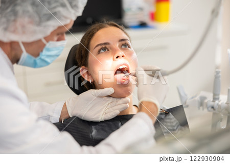Adult male dentist cleaning teeth of female patient Adult male dentist cleaning teeth of female patient 122930904
