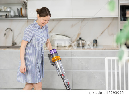 Housewife does cleaning in room - vacuums and dusts Housewife does cleaning in room - vacuums and dusts 122930964