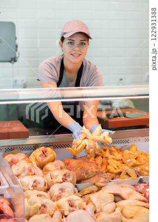 Young woman seller lays out chicken in butcher shop 122931388