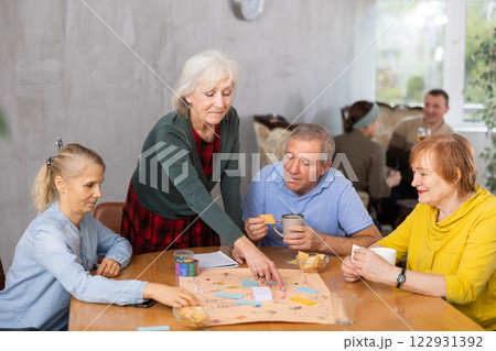 Cheerful elderly woman playing board game with friends 122931392