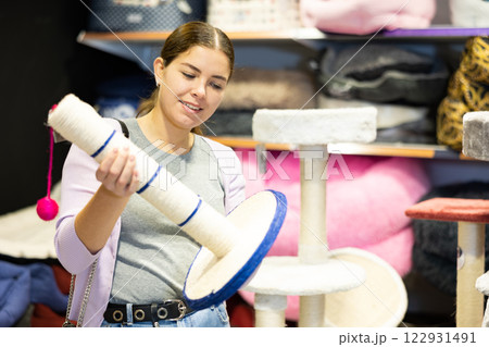 Young woman choosing cat scratching post in pet store 122931491