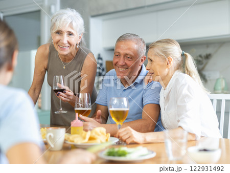 Old men and women talking merrily while having snack in the kitchen 122931492