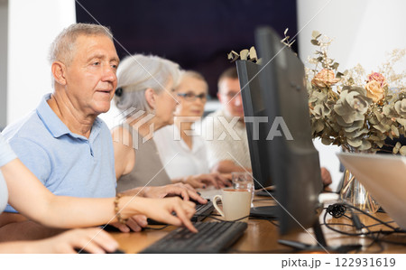 Elderly man taking computer lessons with group of elderly people in nursing home Elderly man taking computer lessons with group of elderly people in nursing home 122931619