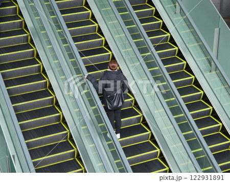 冬の朝の商業施設のエスカレーターに乗る若い女性の姿 122931891