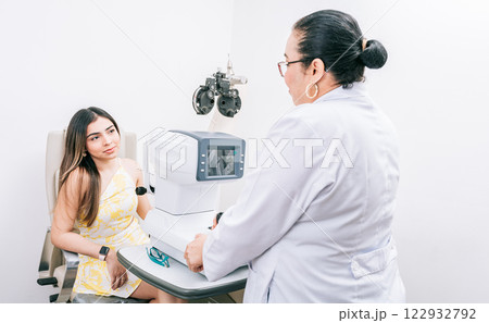 Optometrist with female patient in the autorefractor. Woman patient having consultation with optometrist in office Optometrist with female patient in the autorefractor. Woman patient having consultation with optometrist in office 122932792