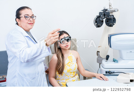 Optometrist assisting patient with optometrist trial frame. Patient with optometrist in a vision test with trial frame 122932798