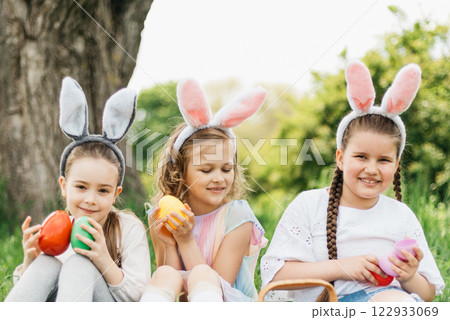 Easter egg hunt. Group Of Children Wearing Bunny Ears Running To Pick Up colorful Egg On Easter Egg Hunt In Garden. Easter tradition 122933069