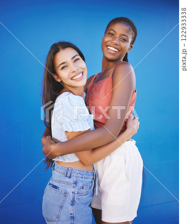 Diversity, friends and women hug with happy smile and woman friendship. Portrait of people smiling embracing love, happiness and female empowerment support in a studio with a blue background 122933338