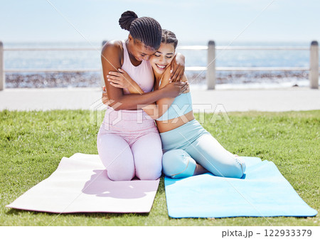Yoga, love and fitness with girl friends hug during a workout, exercise or training by the beach. Sports, health and wellness with a black woman and friend exercising by the sea or ocean Yoga, love and fitness with girl friends hug during a workout, exercise or training by the beach. Sports, health and wellness with a black woman and friend exercising by the sea or ocean 122933379