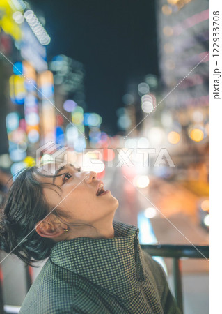 都会の夜景と若い女性ポートレート 122933708