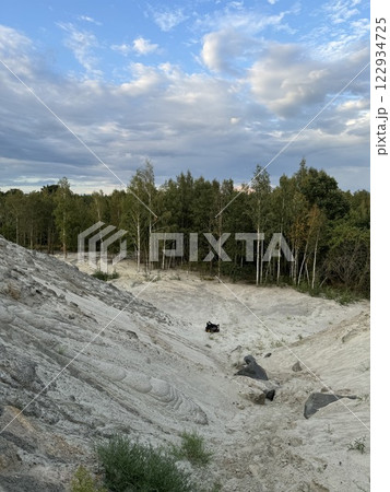 Sandy erosion with scattered rocks near forest under dynamic sky Sandy erosion with scattered rocks near forest under dynamic sky 122934725