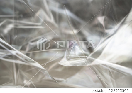 Crumpled clear plastic background, abstract glossy broken surface texture with creases 122935302
