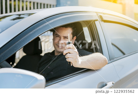 Happy man showing his new car keys, Person in his vehicle showing his car keys, Satisfied car buyer concept, Driver in his car showing the keys out the window 122935562