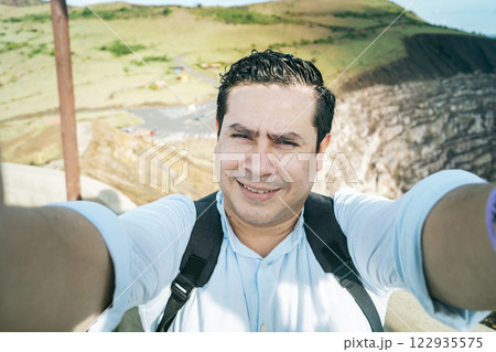 Close up of man taking an adventure selfie, Tourist taking a selfie at a viewpoint. Adventurous people taking a selfie at a viewpoint. Handsome tourist taking a selfie on vacation 122935575