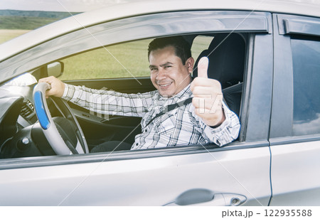 Happy man in his car giving a thumbs up, portrait of a man showing thumbs up while driving, Man in his car giving a thumbs up 122935588