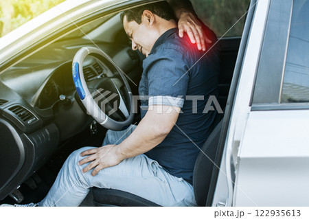 A car driver with muscle pain, concept of a man in his car with neck pain. An exhausted driver with back pain, A person with muscle pain in traffic A car driver with muscle pain, concept of a man in his car with neck pain. An exhausted driver with back pain, A person with muscle pain in traffic 122935613