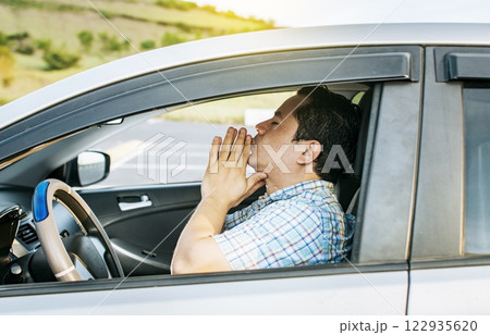 Close up of driver praying in his vehicle, Driver male praying in his vehicle before leaving. Concept of driver man meditating with his hands together 122935620