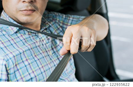 Safety belt for accident prevention. Driver hands fastening the seat belt, Close up of person hands putting on the seat belt. Driver's hands putting on the seat belt 122935622