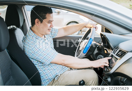 Driver man changing the radio station. Smiling driver tuning into the radio station. Distracted driver concept tuning the radio. Driving people changing radio station Driver man changing the radio station. Smiling driver tuning into the radio station. Distracted driver concept tuning the radio. Driving people changing radio station 122935629